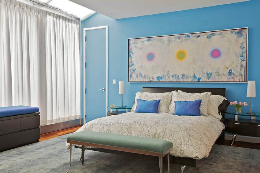 Дверь и стена в спальне окрашены одинаковой голубой краской