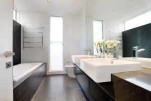 Белые стены ванной комнаты в сочетании с темной плиткой и мебелью