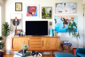 Тумбочка с телевизором в окружении ярких картин и постеров