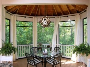 Внутри застекленной беседки размещены кованые стулья и стол Внутри застекленной беседки размещены кованые стулья и стол