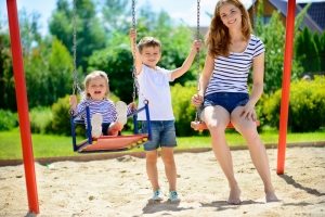 Детские качели, подвешенные к каркасу из металла на цепях Детские качели, подвешенные к каркасу из металла на цепях