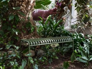 Аккуратная металлическая лавка без спинки в красивом саду Аккуратная металлическая лавка без спинки в красивом саду