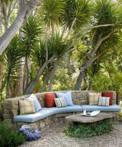 Скамейка, выложенная из натурального камня, с мягкими матрасами и разноцветными подушками Скамейка, выложенная из натурального камня, с мягкими матрасами и разноцветными подушками