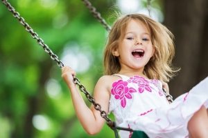 Детские качели, подвешенные к ветке дерева на цепи Детские качели, подвешенные к ветке дерева на цепи