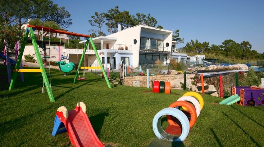 Игровая площадка во дворе частного дома оформлена при помощи использования автомобильных шин, выкрашенных в яркие цвета