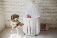 В комнате младенца установлена круглая колыбель с занавесками В комнате младенца установлена круглая колыбель с занавесками