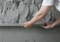 Кирпичные и бетонные стены необходимо предварительно выровнять с помощью черновой штукатурки